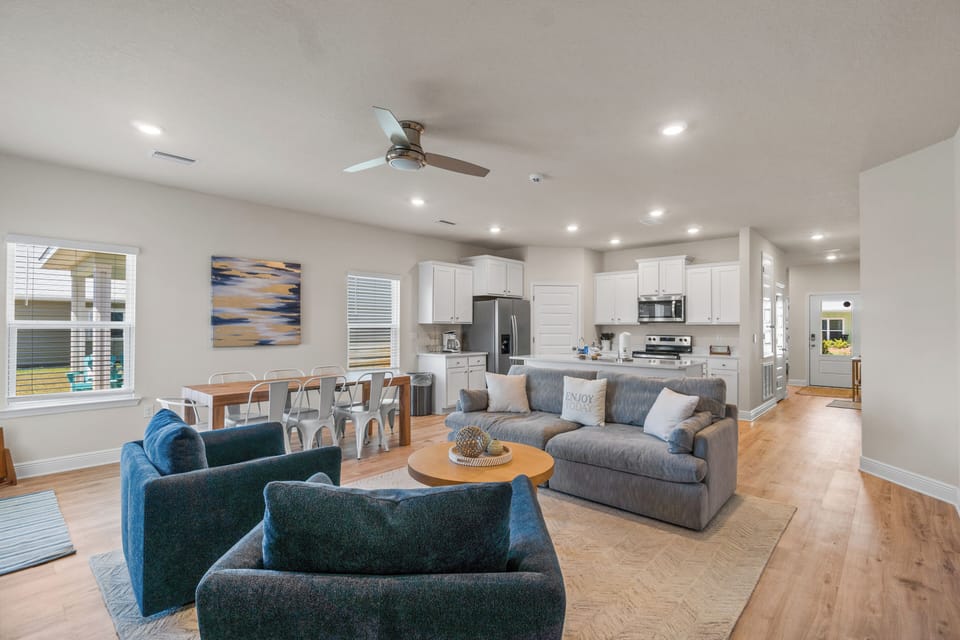 Relax in your spacious open-plan living area where modern comfort meets coastal style, featuring plush seating and a fully-equipped kitchen.