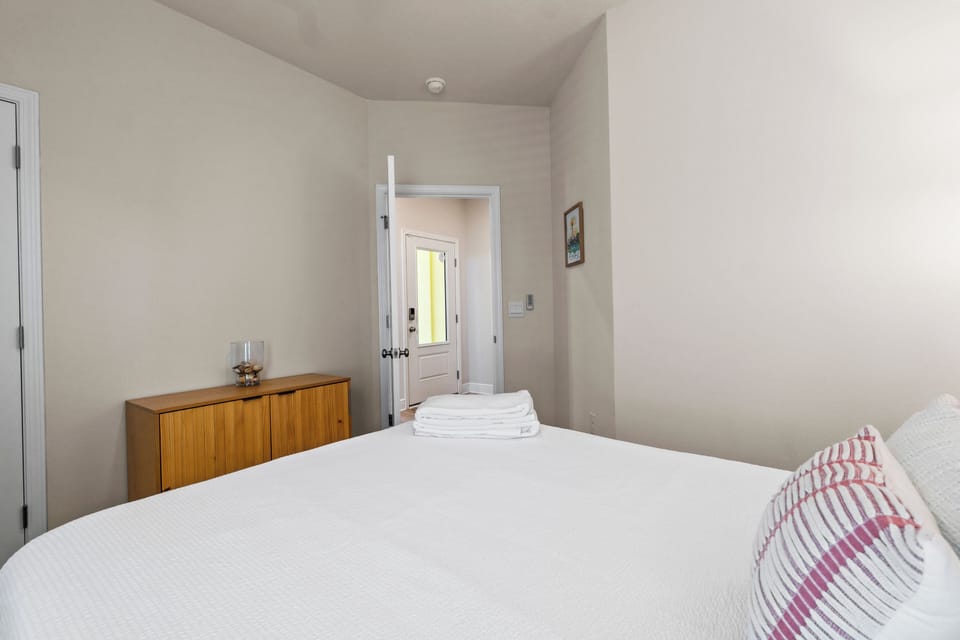 Your serene bedroom awaits with crisp white linens and warm wood accents, creating the perfect retreat for restful nights.