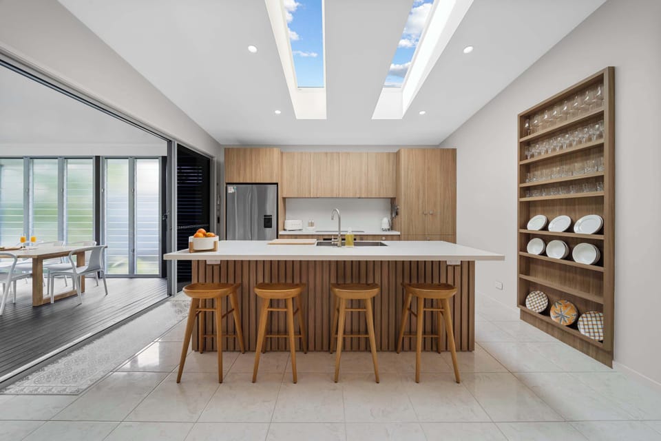 A bright and functional family kitchen enhanced by overhead skylights that fill the space with beautiful natural light. With plenty of bench space, modern appliances, and a leafy outlook, it’s a joy to cook, gather, and entertain in.