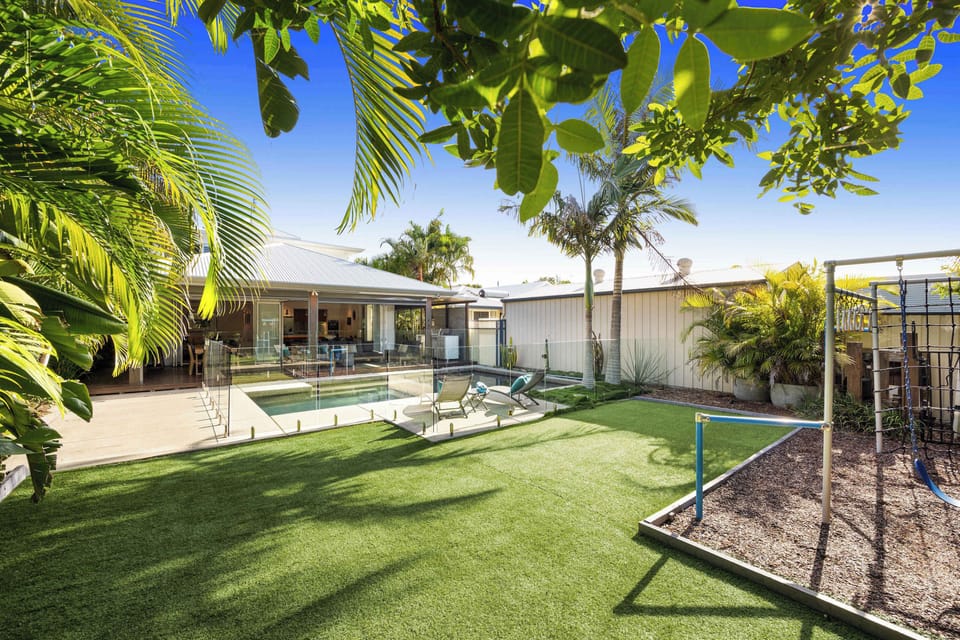 Spacious backyard with children’s swing set and landscaped lawns