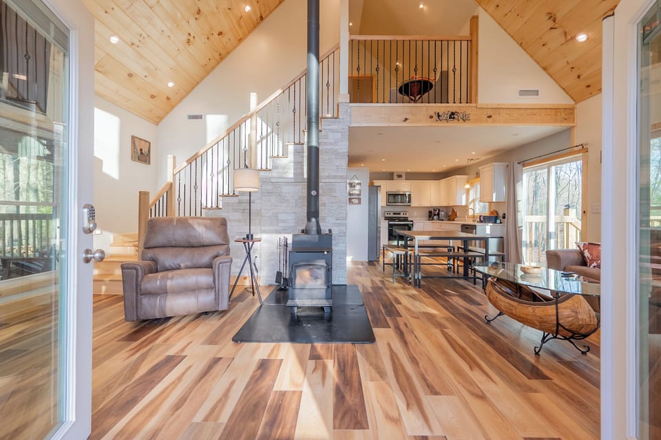 Bright open-plan living with vaulted ceilings and a cozy wood-burning stove.