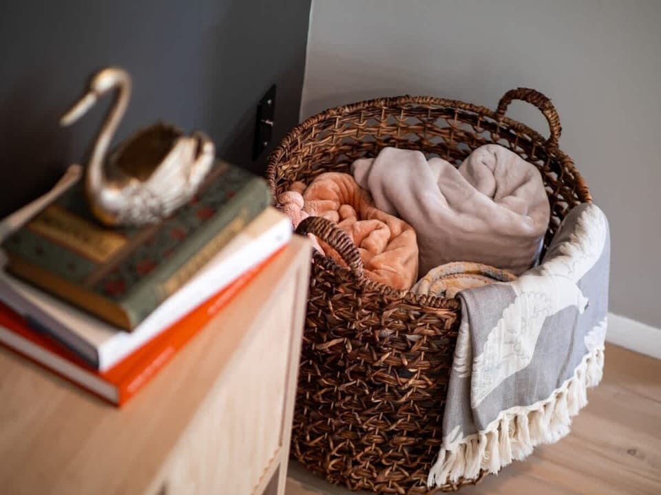 Cozy corner detail w/ stacked books & soft textures for a warm touch