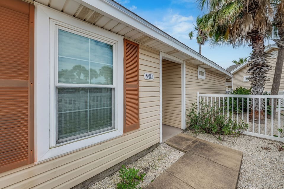 A charming coastal rental with tropical palm trees and clear unit numbering for easy arrival.