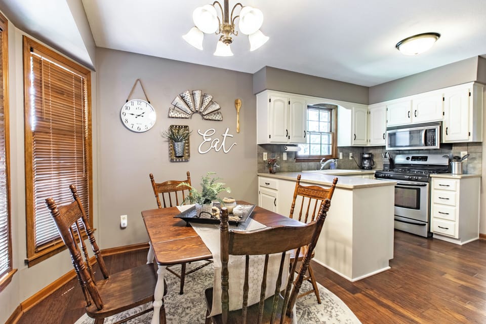 The room features a large wooden table and four matching chairs, perfect for family meals or entertaining guests. A large window with blinds provides ample natural light, creating a bright and cheerful space.



