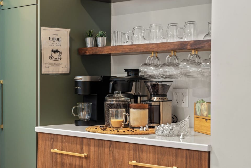 Coffee & Tea Station: Keurig-style maker, thermal drip coffee maker, burr-style grinder with presets, fresh dark roast beans, and an assortment of teas and sweeteners.