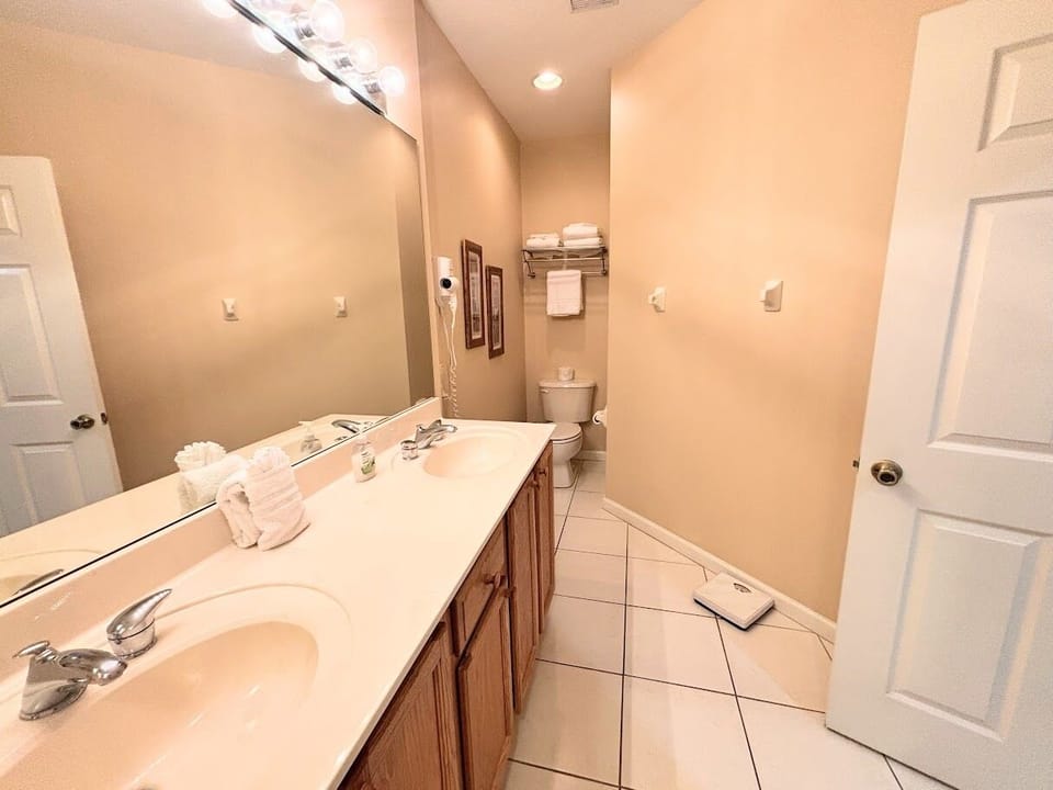 Clean and spacious bathroom featuring a large vanity, bright mirror lighting, tile flooring, and plenty of counter space.