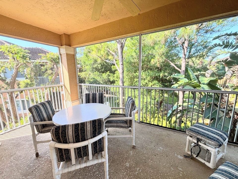 Private screened balcony with outdoor seating, offering a peaceful spot to relax and enjoy the surrounding greenery.