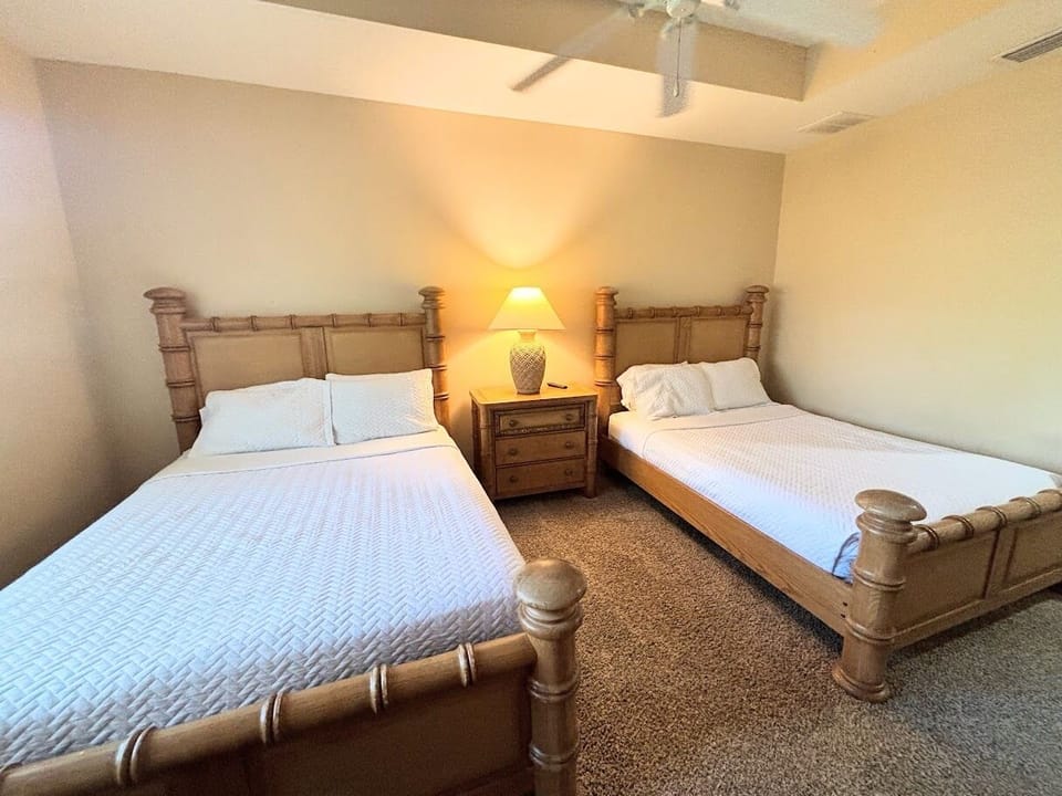 Inviting bedroom with two comfortable beds, matching nightstand, and warm lighting — perfect for guests or family stays.