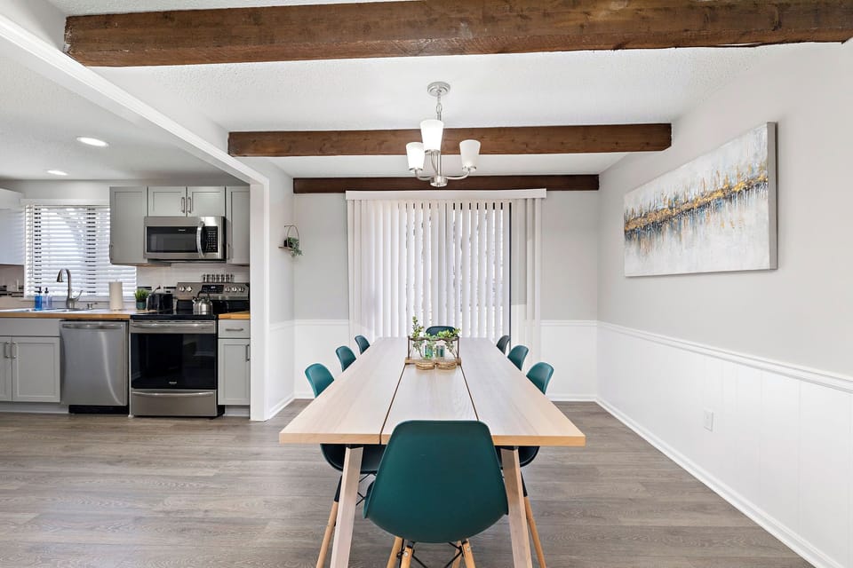 The room boasts high ceilings with exposed wooden beams, adding a rustic and charming touch. The open-concept design allows for seamless flow between the dining area and the adjacent kitchen.