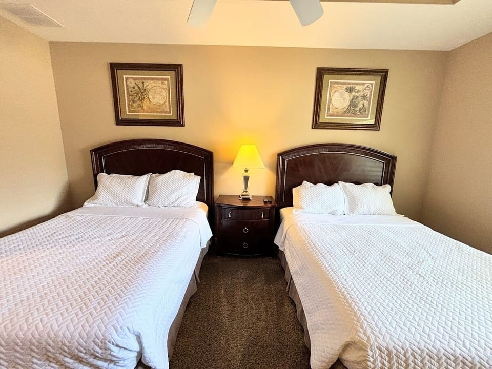 Inviting bedroom with two comfortable beds, matching nightstand, and warm lighting — perfect for guests or family stays.