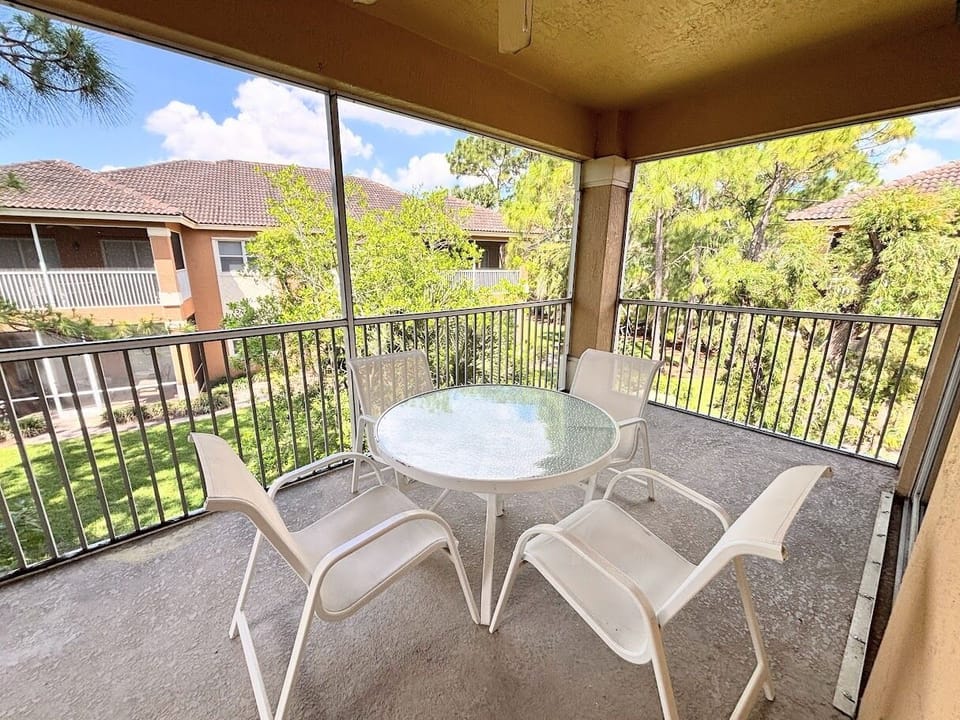 Private screened balcony with outdoor seating, offering a peaceful spot to relax and enjoy the surrounding greenery.