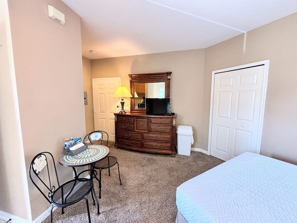 Bedroom sitting area with a small table, dresser storage, TV, and closet access.