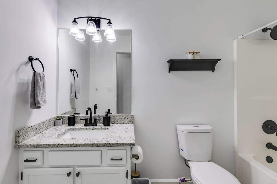The shared hallway bath is minimally decorated with decor matching fixtures.