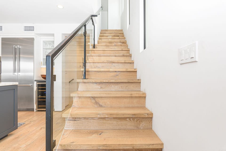 Follow the staircase upward, where warm wood tones and clean architectural lines lead you to the third level
                