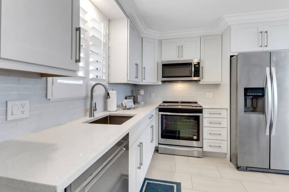 The fully remodeled and updated kitchen features quartz counters, glass tile backsplash and full-size upgraded appliances.
