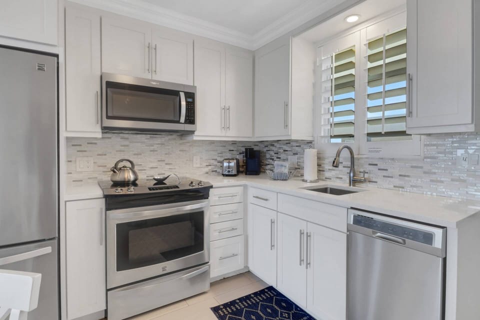 The fully remodeled and updated kitchen features quartz counters, glass tile backsplash and full-size upgraded appliances.