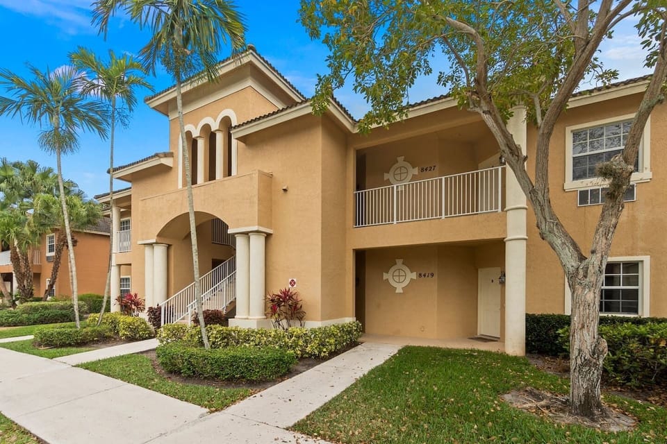 Exterior view of the building with tropical landscaping, covered entryways, and Florida-style architecture.