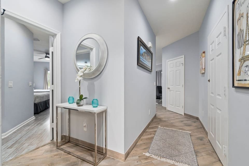 Bright hallway and entry area with decorative accents, wood-look flooring, and access to the bedrooms and living spaces.