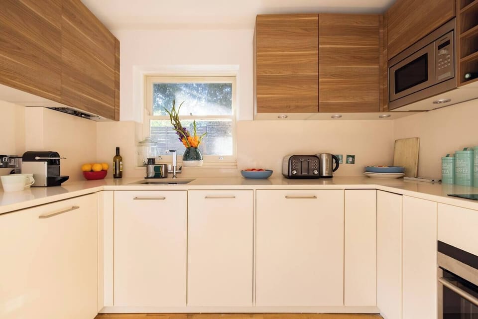 Indulge in our fully equipped kitchen, featuring a sink with a charming glass window, a pristine white countertop, and elegant maple overhead cabinets.