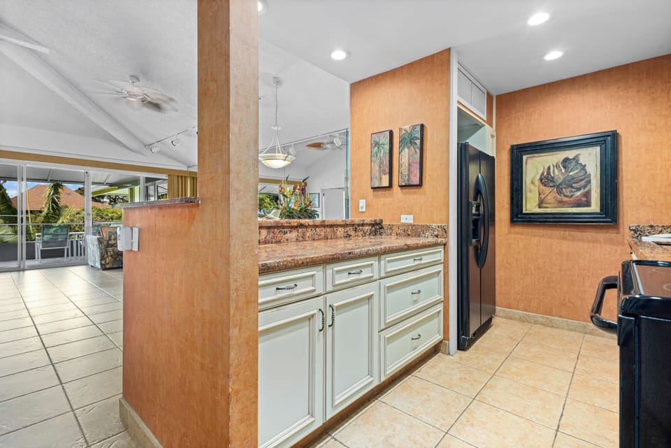 A fully-equipped kitchen with granite countertops, tropical artwork, and open sightlines welcomes you to prepare meals with ease and island-inspired charm throughout your stay.