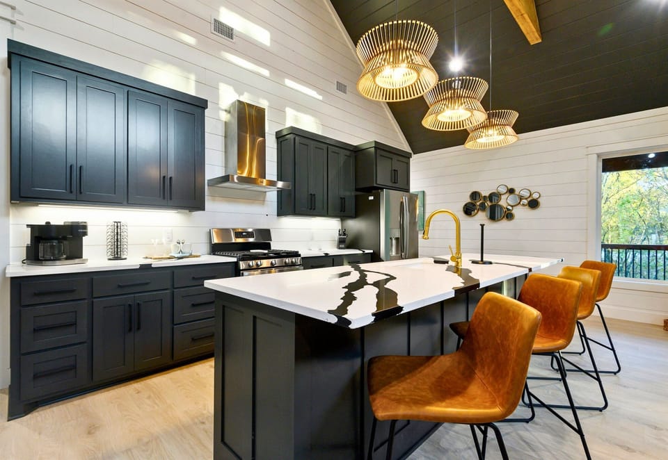 The kitchen is both bold and welcoming, with rich dark cabinets, sleek countertops, and statement lighting that sets the stage for cooking, chatting, and memory-making.