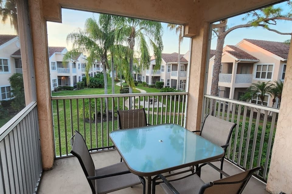 Private screened balcony with outdoor dining space and peaceful views of the surrounding community grounds.