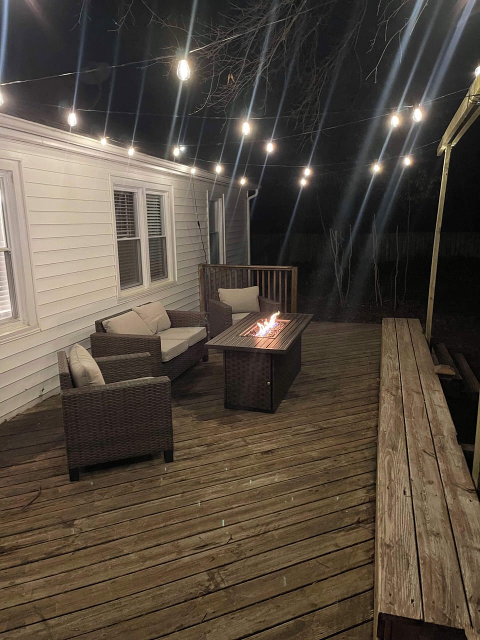 View of the back deck at night featuring our string lights and table top fireplace.