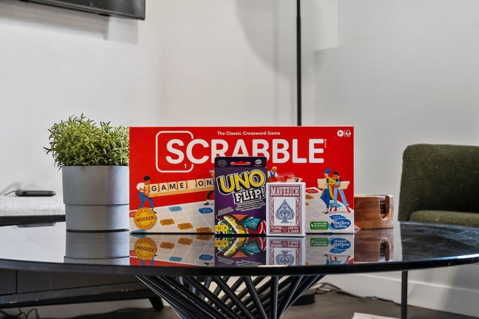 Living room with a Smart/cable TV, selection of board games & cozy seating options.