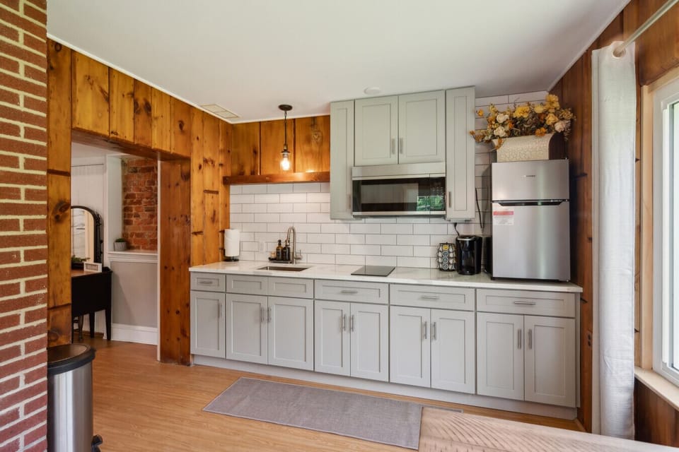 Bright kitchen w/ white cabinets, wood-paneled walls & stainless steel appliances