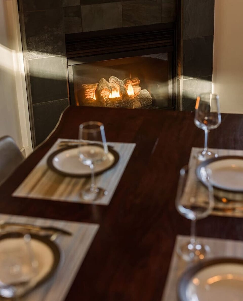 The dining table is next to the gas fireplace