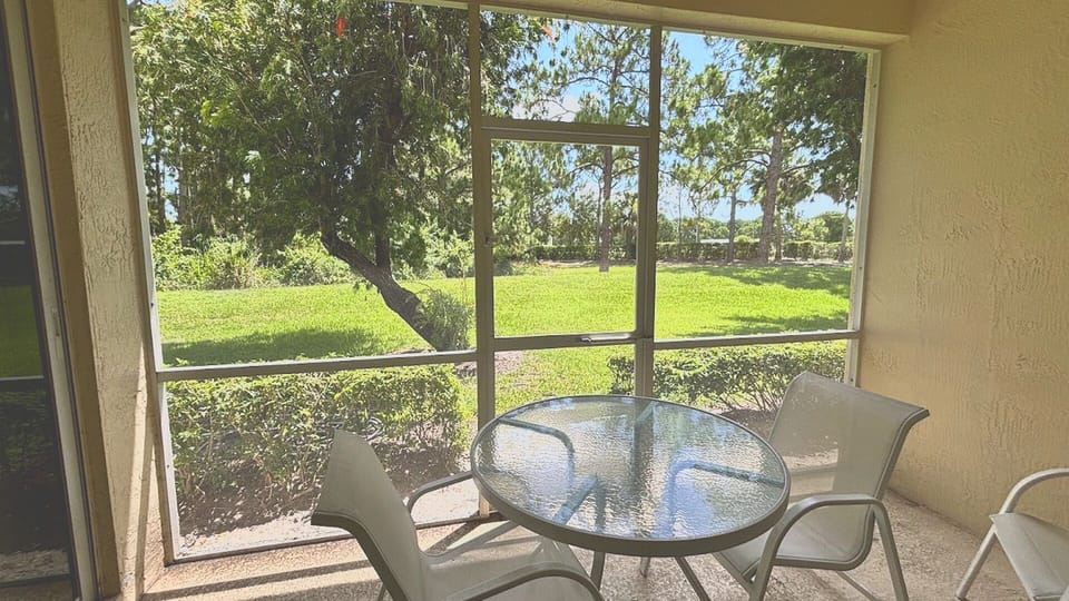 Enjoy bug-free outdoor living on your private screened-in patio, complete with a glass-top table set overlooking a beautifully manicured green lawn.