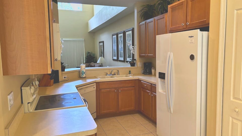The chef's kitchen features warm wood cabinetry, extensive counter space, and a unique open-ceiling view to the upper level, keeping the space feeling connected and bright.