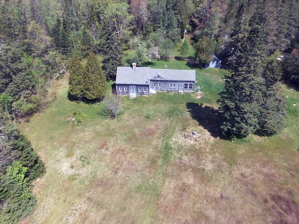 Drone shot looking at the house from the water