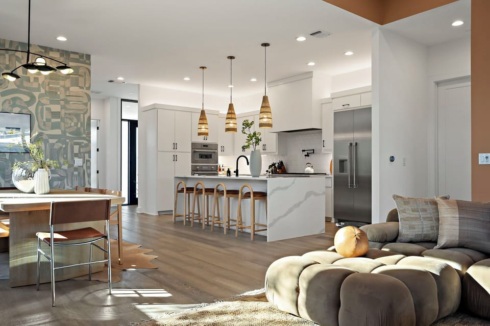 Bright and open living space seamlessly blending a modern white kitchen with a stylish dining area and a comfortable lounge, all bathed in natural light