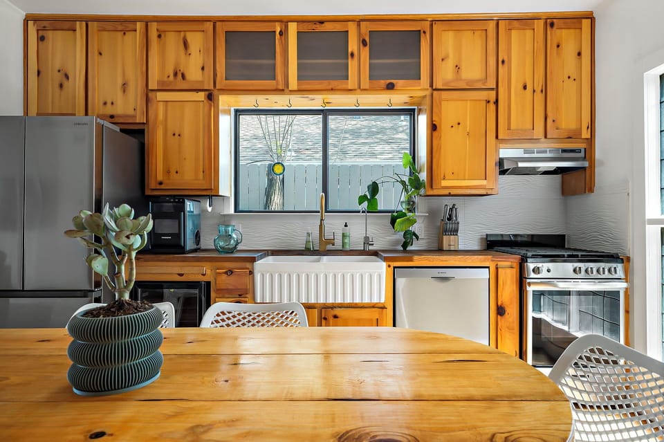 Rustic and cozy kitchen in a charming cottage. This kitchen features knotty pine cabinetry, a farmhouse sink, and modern appliances, creating a warm and inviting space for cooking and gathering.