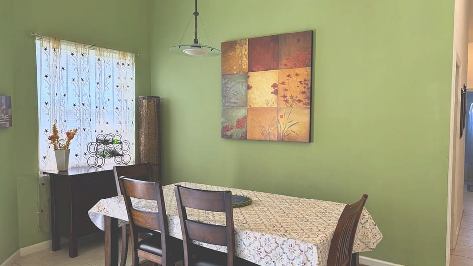 Perfect for family dinners or entertaining friends, this cozy dining area features a warm, inviting sage-green accent wall and stylish wall art.