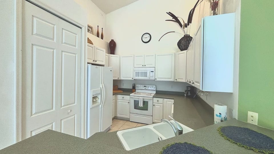 A bright and efficient kitchen equipped with crisp white cabinetry, full-sized appliances, a breakfast bar pass-through, and a spacious pantry closet for all your storage needs.