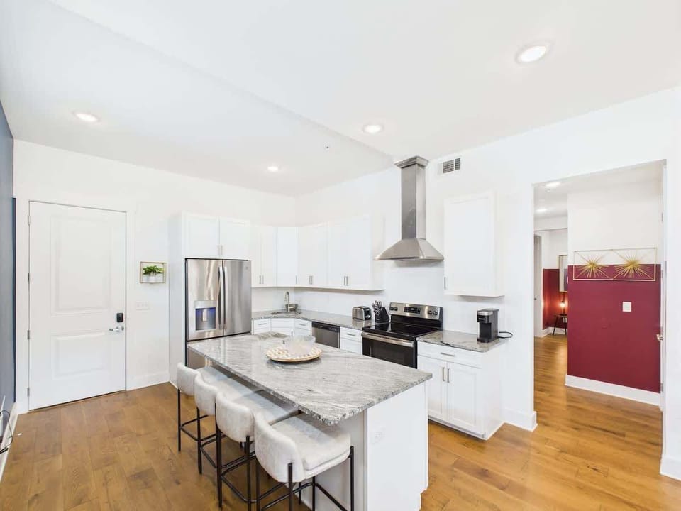 The fully equipped modern kitchen features culinary essentials, stainless steel appliances, and island bar seating.