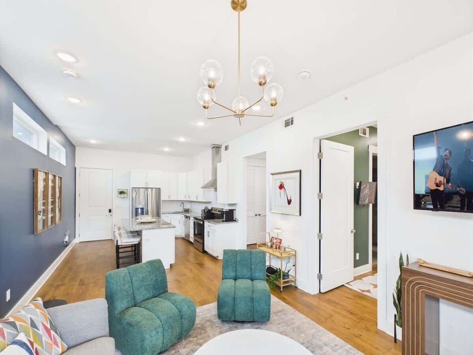 Bright open floor living space featuring a smart flat-screen TV, designer furnishings, and a private balcony entrance.