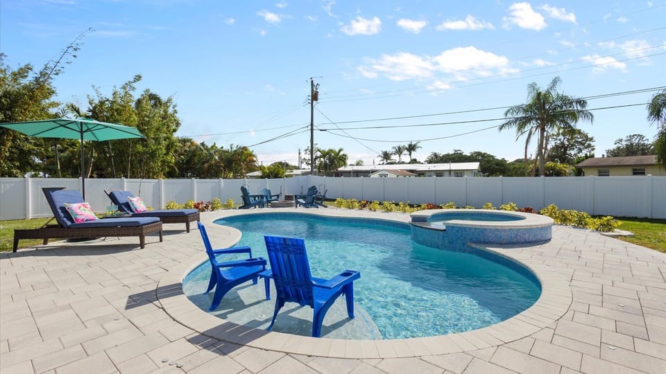 Relax in your private, fully fenced backyard with a heated pool, shallow sun shelf, sun loungers, in-water seating, and a sitting area with firepit at the edge of the pool deck.