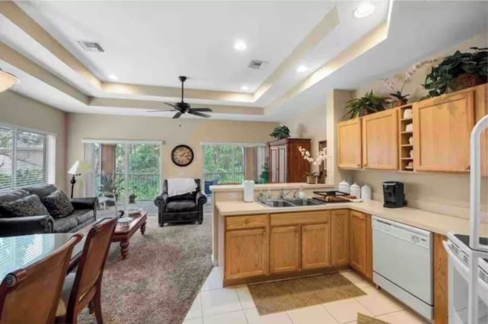 Open kitchen and living area featuring tray ceilings, full-size appliances, breakfast bar seating, and plenty of natural light.