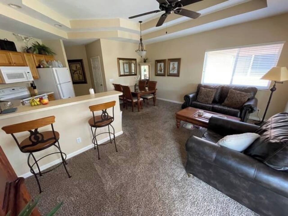 Comfortable living and dining area with cozy seating, breakfast bar seating, and large windows for natural light.