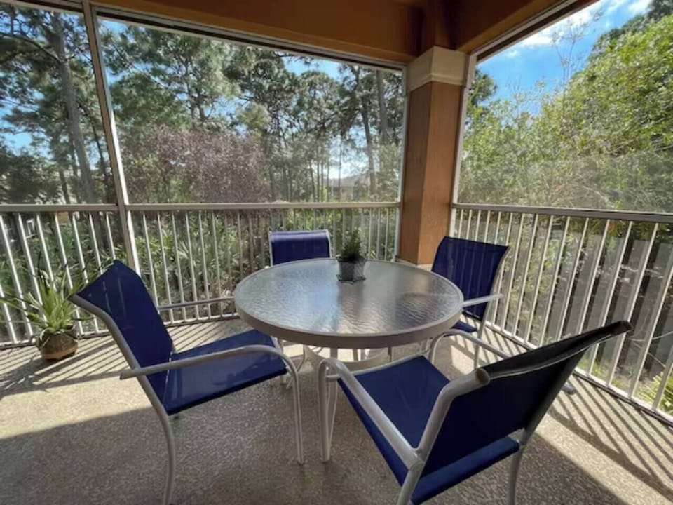 Private screened balcony with outdoor seating and peaceful views of the surrounding greenery.