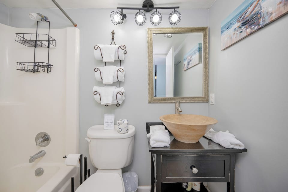 Warmed by soft lighting, the guest bath invites quiet moments by the elegant vessel sink and tub