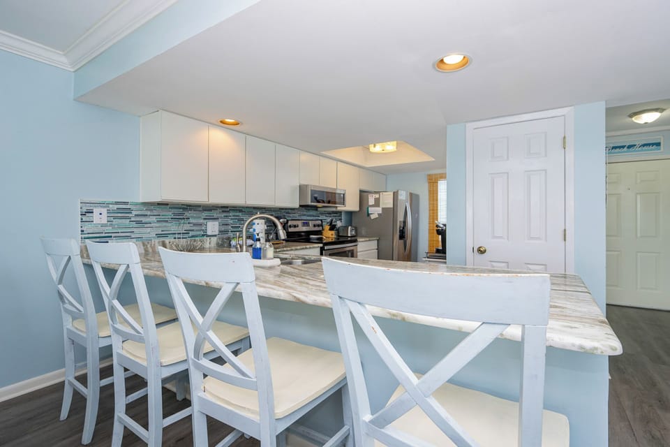 This modern kitchen features sleek stainless appliances, a stylish backsplash, and a breakfast bar perfect for casual dining