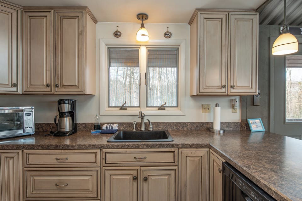 - Bright kitchen window view bringing in natural light   - Plenty of counter space for preparing group meals   - Comfortable cooking space in a Vermont cabin retreat
