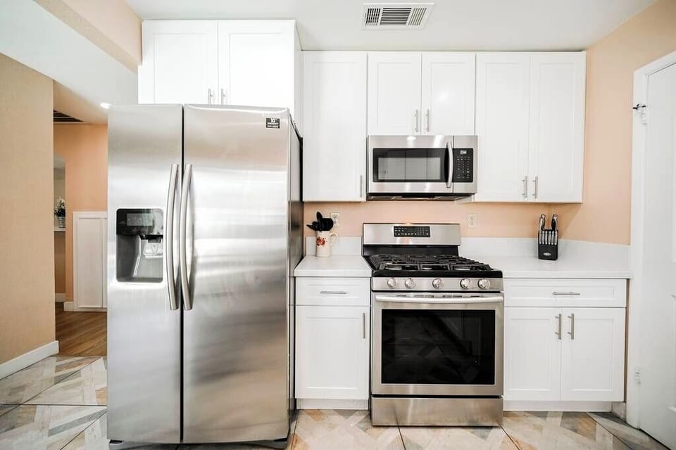 Modern kitchen with white cabinetry and stainless steel appliances.