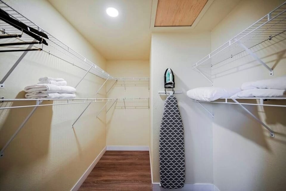 Compact walk-in closet with shelves and an ironing board.