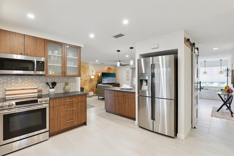 The kitchen features wooden cabinetry, a two door refrigerator, a stove, and an oven.