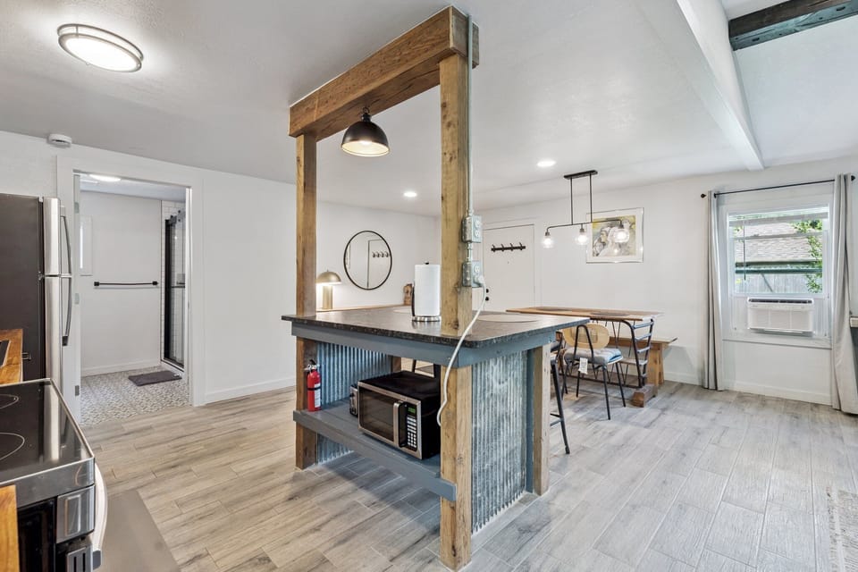 Industrial-chic kitchen island with open shelving, rustic wood beams, and corrugated metal detail—ideal for cooking or casual counter seating. Enjoy direct flow to the cozy dining nook and open-concept layout.